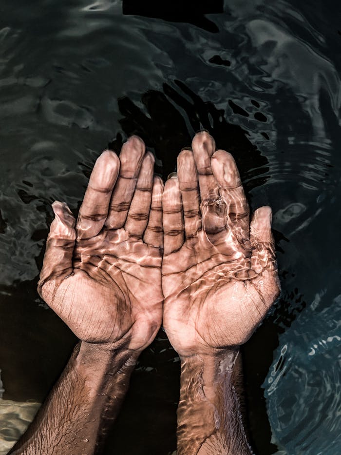 From above of crop anonymous male washing hands in clean water of lake in daytime